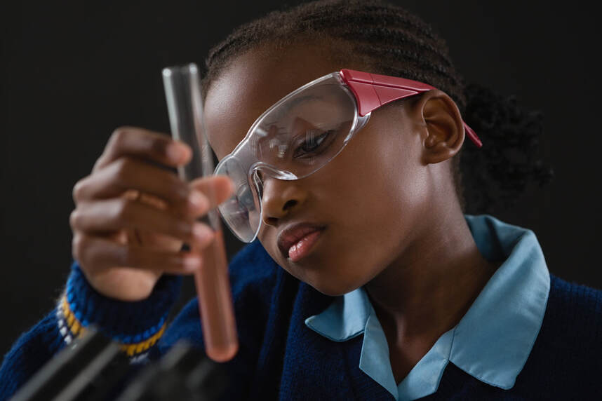 girl wearing goggles holding a test tube