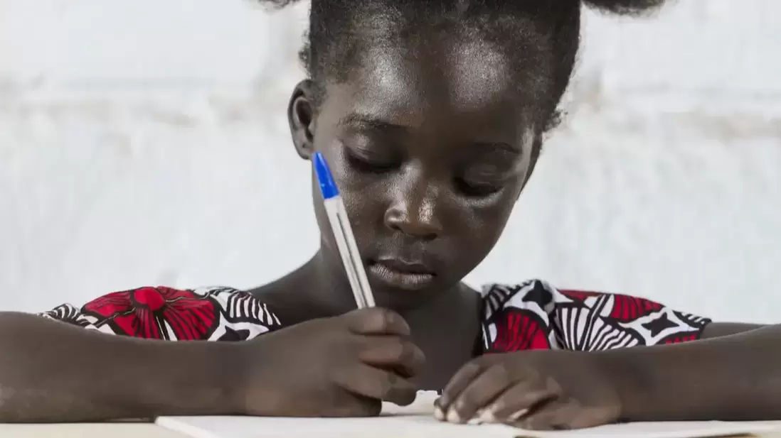 A young girl writing on a book