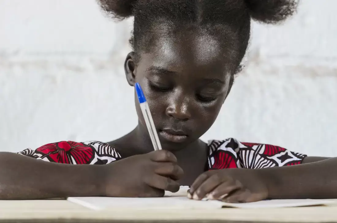 A young girl writing on a book