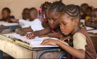 two little african girls classmates sitting in class reading a book